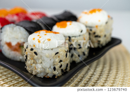 Assorted sushi rolls with cream cheese and fish toppings on black plate Assorted sushi rolls with cream cheese and fish toppings on black plate 123679740