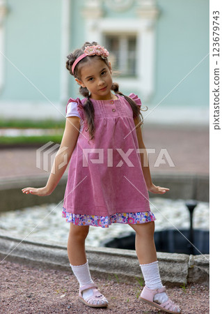 Young caucasian girl in pink dress posing outdoors near fountain Young caucasian girl in pink dress posing outdoors near fountain 123679743