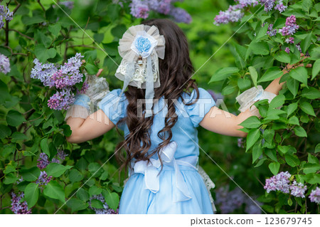 Young caucasian girl in blue dress with long hair among lilac bushes Young caucasian girl in blue dress with long hair among lilac bushes 123679745