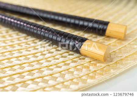 Detailed view of traditional bamboo chopsticks on woven mat surface Detailed view of traditional bamboo chopsticks on woven mat surface 123679746