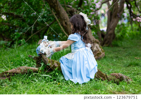 Young brunette girl in blue dress playing with toys in forest Young brunette girl in blue dress playing with toys in forest 123679751