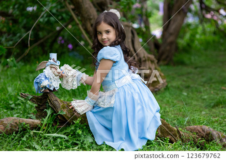 Young caucasian girl in blue dress playing in forest with toy rabbit Young caucasian girl in blue dress playing in forest with toy rabbit 123679762