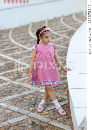 Caucasian young girl in pink dress standing outdoors Caucasian young girl in pink dress standing outdoors 123679842