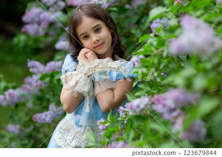 Caucasian young girl in blue dress with flowers in garden Caucasian young girl in blue dress with flowers in garden 123679844