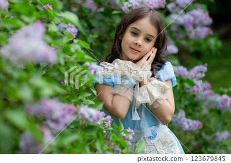 Young caucasian girl in blue dress with lilac flowers in garden 123679845