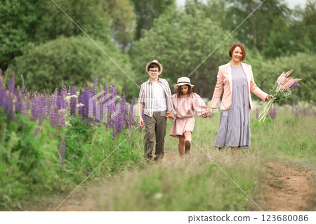 Mother with children walking in meadow holding flowers Mother with children walking in meadow holding flowers 123680086