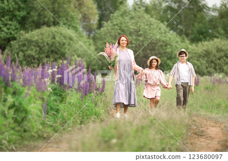 Caucasian young woman with children walking in lavender field holding flowers Caucasian young woman with children walking in lavender field holding flowers 123680097