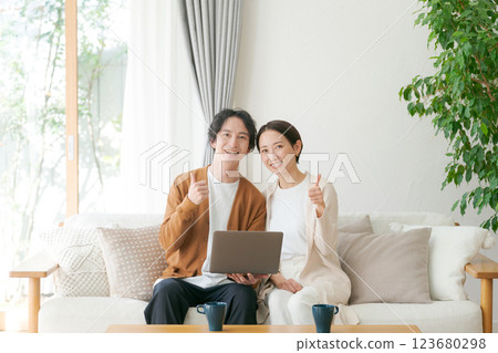 A couple sitting on a sofa looking at a computer 123680298