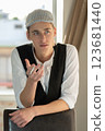 A young man in a cap, a vest, a white shirt, smokes by the window and talks. Bad habits among young people. Young manager. 123681440