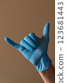A person who is wearing a bright blue glove is making a wellrecognized peace sign with their fingers in a positive and friendly gesture 123681443