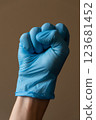 A person who is wearing a bright blue glove is making a wellrecognized peace  123681452