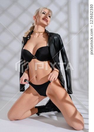 Woman models stylish black lingerie with leather jacket in modern setting Woman models stylish black lingerie with leather jacket in modern setting 123682380
