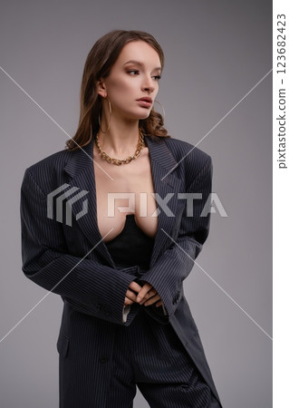 Sophisticated woman in a tailored suit showcasing lingerie in a studio Sophisticated woman in a tailored suit showcasing lingerie in a studio 123682423
