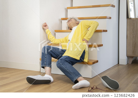 Senior woman holding her back after falling down the stairs at home Senior woman holding her back after falling down the stairs at home 123682426