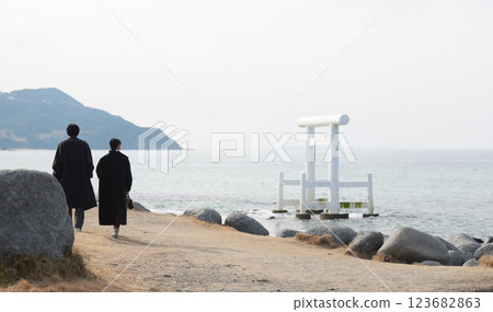 couple walk on waterfront of Sakurai Futamigaura torii in Itoshima, Fukuoka which in front of  Married Couple Rocks 123682863