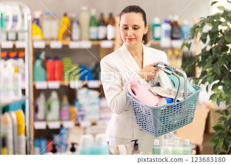 Adult woman with basket chooses household chemicals 123683180