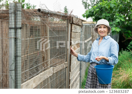 Mature smiling female farmer posing near village house 123683287