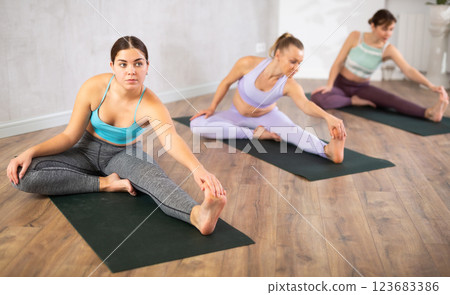 Group of women doing leg warm-up during yoga class 123683386