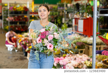 Cheerful girl choosing floral arrangement amidst flower market stalls Cheerful girl choosing floral arrangement amidst flower market stalls 123683400