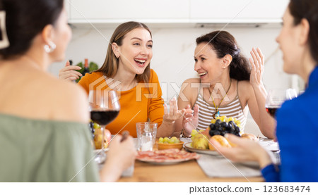 Four women are sitting at table, enjoying food and wine, chatting, talking, laughing. Four women are sitting at table, enjoying food and wine, chatting, talking, laughing. 123683474