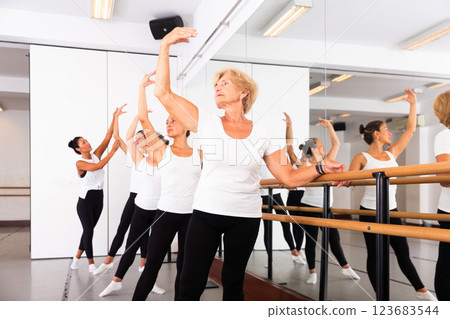 Female ballet trainer teaching group of dancers near ballet barre in dancing hall 123683544