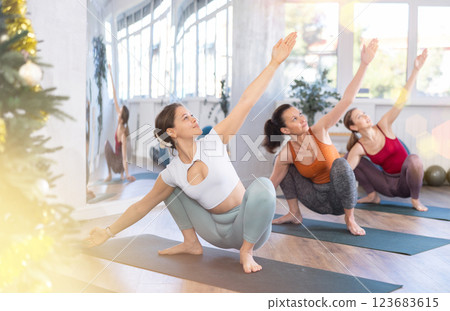 Women during yoga class with group in fitness studio decorated with Christmas tree Women during yoga class with group in fitness studio decorated with Christmas tree 123683615