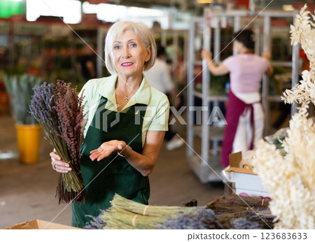 Elderly woman, hostess of the flower market, collects lavender in bouquet 123683633