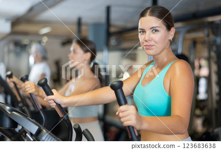 Sporty girl working out on elliptical machine in gym. Healthy active lifestyle concept Sporty girl working out on elliptical machine in gym. Healthy active lifestyle concept 123683638