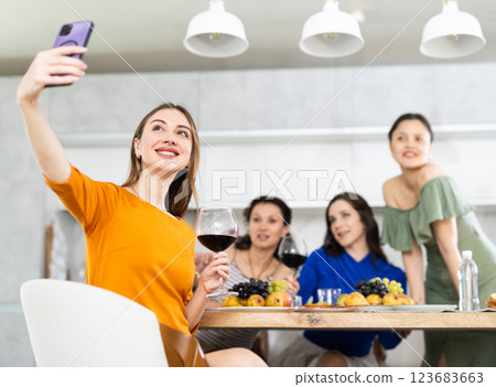 Smiling woman taking selfie with friends at home get-together Smiling woman taking selfie with friends at home get-together 123683663