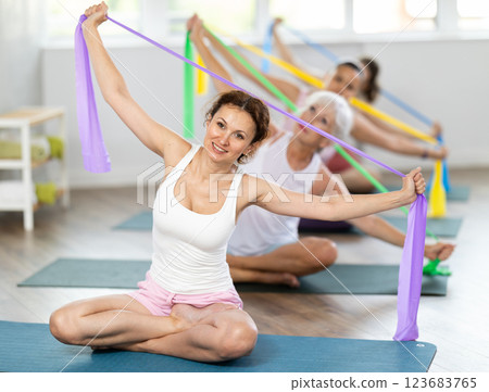 Woman exercising with resistance band in group fitness class 123683765