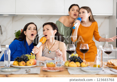 Group of female friends are having fun singing karaoke during feast and gatherings. Group of female friends are having fun singing karaoke during feast and gatherings. 123683768