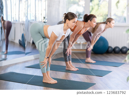 Happy woman standing yoga pose and making full body stretching workout with group people in sports room 123683792