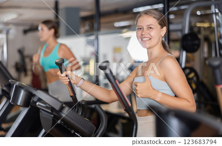 Sporty girl working out on elliptical machine in gym. Healthy active lifestyle concept Sporty girl working out on elliptical machine in gym. Healthy active lifestyle concept 123683794