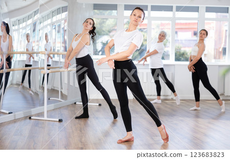Group of slender women of different ages are learning various dance and ballet movements in studio 123683823