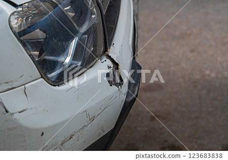 The front bumper of a white car with numerous minor injuries in form of scratches, chips, tears. Minor road traffic accidents that impair the integrity of the protective paint on the hull elements 123683838