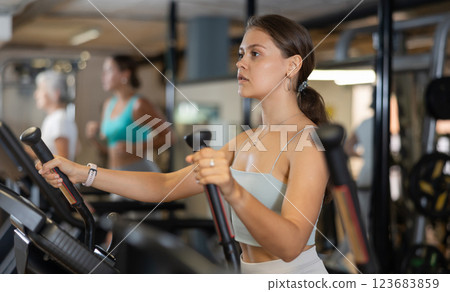 Portrait of sporty woman doing cardio workout on elliptical cross trainer at fitness center Portrait of sporty woman doing cardio workout on elliptical cross trainer at fitness center 123683859