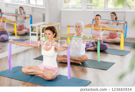 Fit woman performing resistance band exercises at group fitness class 123683934