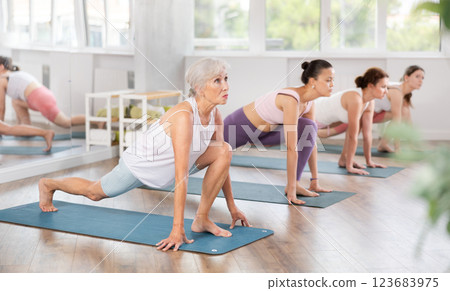 Women practicing in yoga class, focusing on flexibility and relaxation in calm studio setting Women practicing in yoga class, focusing on flexibility and relaxation in calm studio setting 123683975