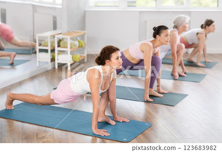 Woman performing Low Lunge Pose with group in yoga studio Woman performing Low Lunge Pose with group in yoga studio 123683982