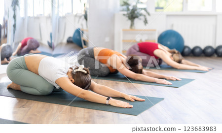 Women performing Bhujangasana or Cobra pose during yoga class with group in fitness studio Women performing Bhujangasana or Cobra pose during yoga class with group in fitness studio 123683983