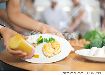 Womens hands decorate tender baked chicken fillet with sauce. Group lesson cooking courses. Close-up 123683999