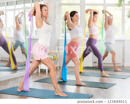 Women are doing stretching exercise with resistance bands in gym. Teamwork, good mood and healthy lifestyle concept Women are doing stretching exercise with resistance bands in gym. Teamwork, good mood and healthy lifestyle concept 123684011
