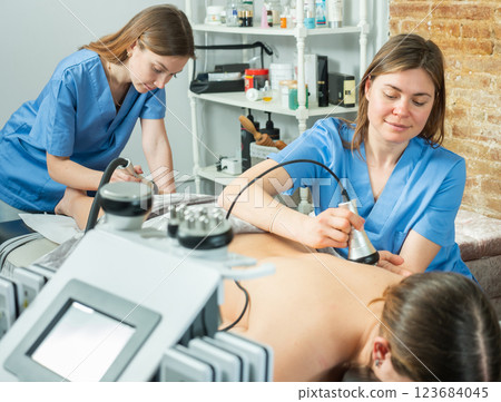 Women doctors performing hardware body procedure to female patient 123684045