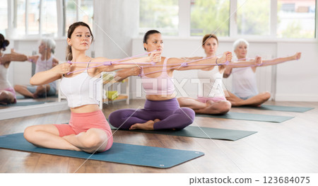 Girl strengthening muscles with figure eight exercise band in fitness studio 123684075