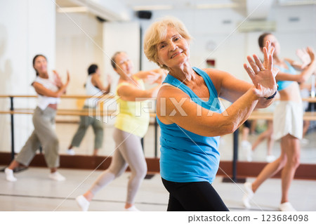 Portrait of mature woman practicing ballet dance moves during group class in choreographic studio 123684098
