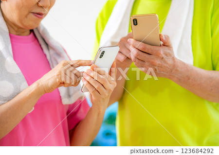 Senior men and women who look at their smartphones after exercise and worry about the results Senior men and women who look at their smartphones after exercise and worry about the results 123684292