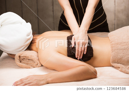 A young Asian woman has her back wiped with a towel. 123684586