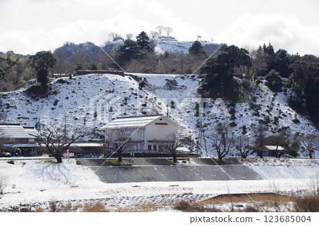 The snow-covered Gassan Toda Castle ruins and the roadside station at the foot of the mountain, illuminated under the bright winter sky: Hirose Town, Yasugi City, Shimane Prefecture 123685004