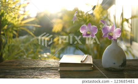 old notebook and vase of pink orchid flowers, cozy outdoor garden 123685481