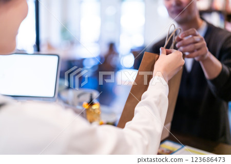 Smiling restaurant employee handing over a product, no face 123686473